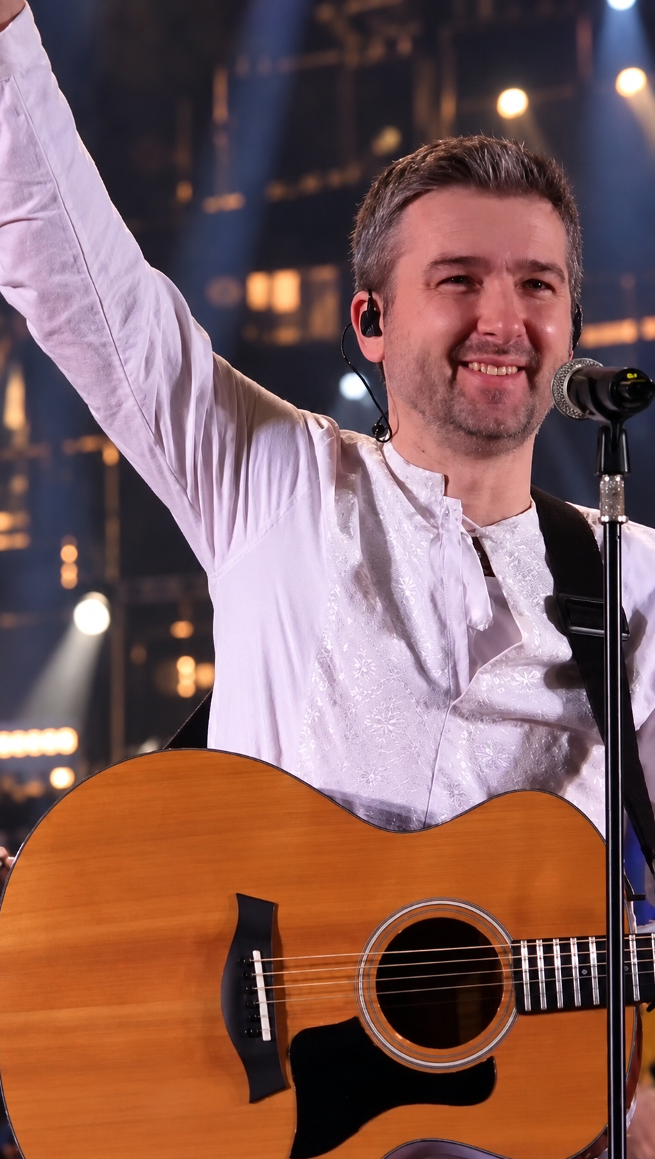 Black-and-white photo of Kostya Leontovich performing on stage with an acoustic guitar